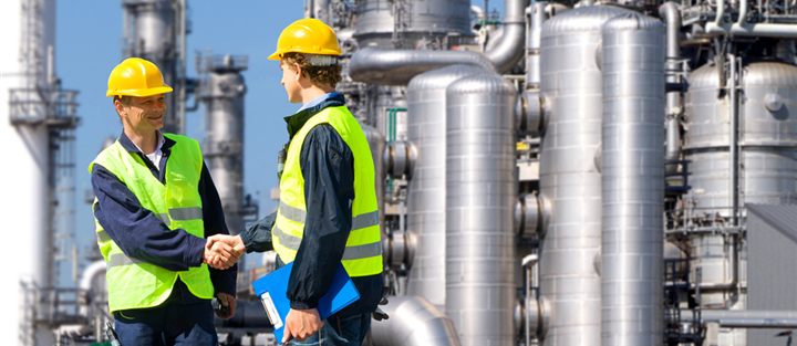 Poignée de main entre partenaires industriels devant une installation de production